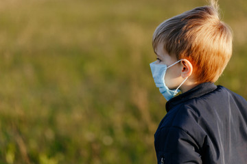 Little boy wearing the medicing mask while walking outside