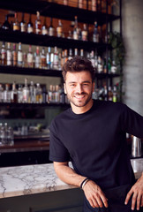 Fototapeta na wymiar Portrait Of Confident Male Owner Of Restaurant Bar Leaning Against Counter