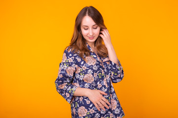 Cute and cheerful woman in home wear pajama studio lifestyle yellow background emotions.