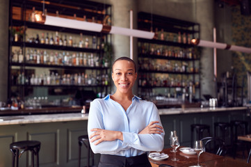 Portrait Of Confident Female Owner Of Restaurant Bar Standing By Counter