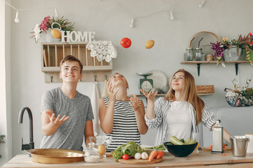 F in a kitchen. Blonde in a white t-shirt. Woman with vegetables