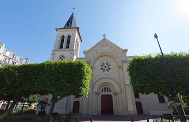 Saint Justin Catholic Church: Religious building in neo-medieval style with bell tower and spire. Levallois-Perret, France, Europe