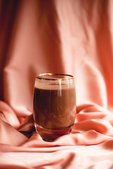 A glass of cocoa on a pink, silk cloth. Tasty drink.
