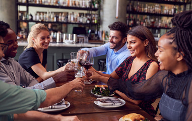Group Of Friends Meeting In Restaurant Celebrating And Making A Toast