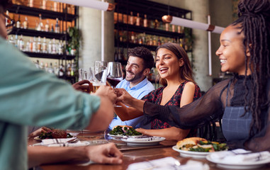 Group Of Friends Meeting In Restaurant Celebrating And Making A Toast