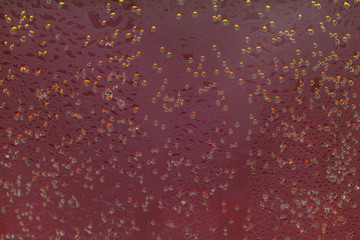 Soda sparkling drink little bubbles with glass red surface background macro
