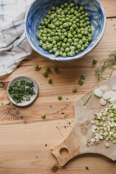 Bol de petits pois crus et herbes, sur une table en bois