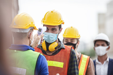 Officer checking fever team engineer and technician foreman with digital thermometer in cargo container shipping. Prevent the outbreak of the virus covid-19.