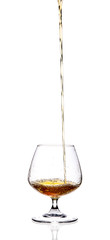 a glass in which a long stream of brandy, cognac, whiskey is poured on a white highlighted background