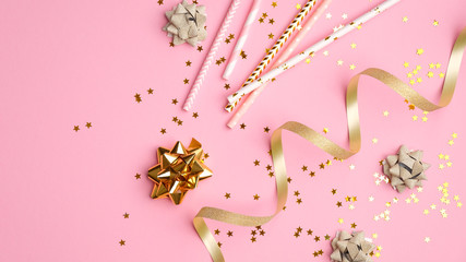 Golden streamers and confetti on pink background. Christmas, birthday or wedding concept. Flat lay, top view.