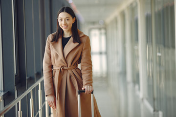 Woman at the airport. Girl with suitcase. Lady in a brown coat.