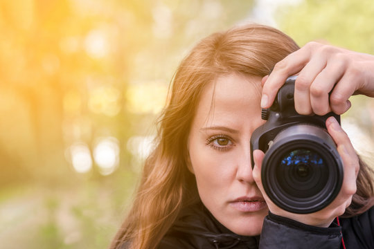 photographer girl, close-up portrait. The girl model takes photos, looking at the viewer and into the lens of the outdoor camera. red hair develop, copyspace