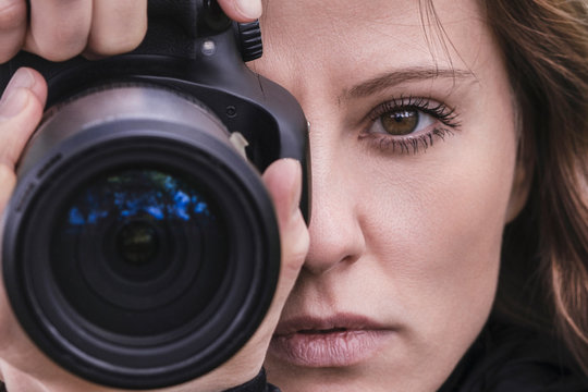 Close-up of a female photographer's face. A beautiful girl takes photos and looks into the camera