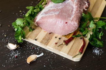 greens, seasonings and meat on a cutting board. a piece of pork, pepper, garlic, salt. Cook at...