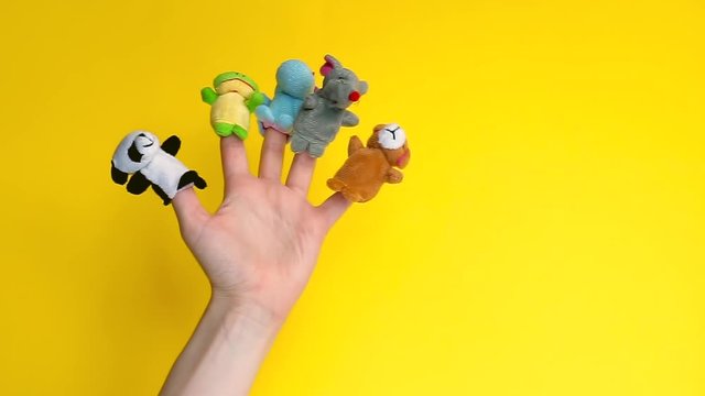 Animals zoo puppet dolls theater. Hand wearing finger puppets: elephant, frog, dog, rabbit, hippo,bear, panda. animal finger puppets show on yellow background. quarantine fun. template mock up.