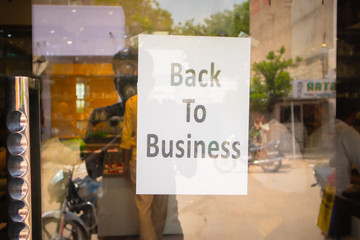 Back to business poster or signage sticked in front of store door - concept of reopening business after coronavirus or covid-19 pandemic lockdown crisis.