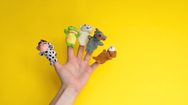 Puppet theater doll animals. Hand wearing finger puppets: cow, frog, dog, rabbit, mouse, bear. animal finger puppets show isolated on yellow background. family quarantine fun. template mock up. 