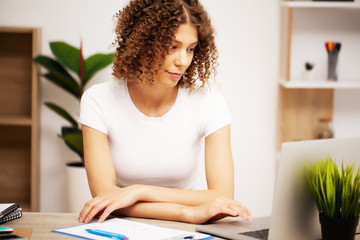 Attractive business woman working on laptop in her workstation.