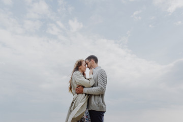 Young woman and man hug and kiss on sky background.