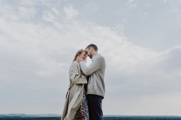 Young woman and man hug and kiss on sky background.