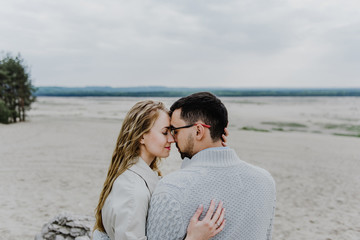 Young woman and man hug and kiss in a sand quarry.