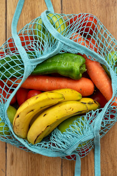Cotton string eco bag with fruits and vegetables on wooden background