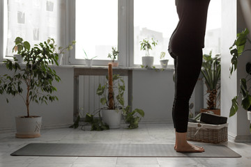 woman wearing black clothes does yoga at home. gray yoga mat and black yoga blocks in a nice busket...