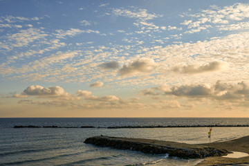 Elevated view of an empty beach with rocky breakwaters and dramatic sky at sunset, Sanremo, Imperia, Liguria, Italy