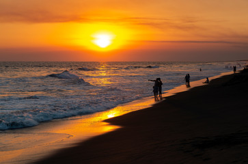 Sunset along the volcanic sand beach of Monterrico with the silhouette people, Pacific Ocean, Guatemala.