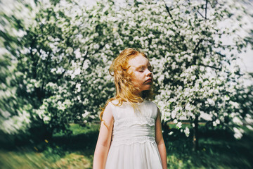 Fototapeta na wymiar portrait of a little red-haired girl in Apple trees