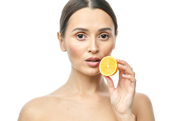 Close up beauty portrait of an excited attractive half naked woman holding Meyer lemon slices at her face and looking at camera isolated over white background