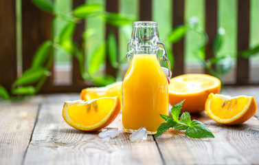 Fresh orange juice with oranges fruit outdoors on a wooden table.