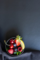 Summer fruits, berries and mint in chalk painted glass of juice on black background. Conceptual healthy, vitamin, diettary food. Vegan, vegetarian and detox food and drinks. Menu mock up, poster