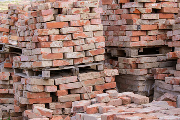 Pile of old brown bricks packed on a pallet. Industrial waste concept.