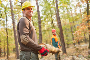 Zwei Forstarbeiter tragen Baumstamm bei Holzernte