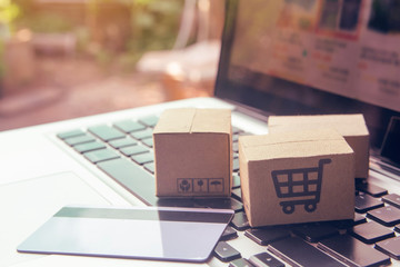 Online shopping - Paper cartons or parcel with a shopping cart logo and credit card on a laptop keyboard. Shopping service on The online web and offers home delivery..