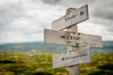 help stop coronavirus text engraved on wooden signpost outdoors in nature.