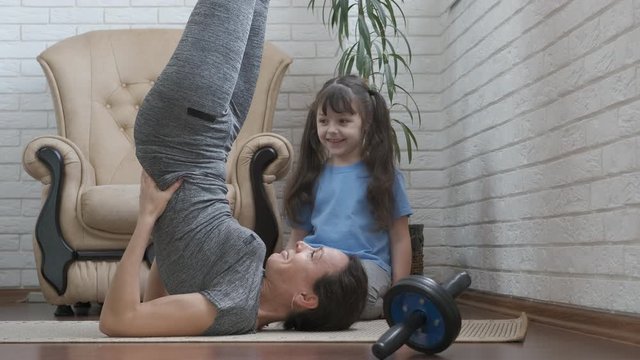 Sports with mom. Cute little girl is engaged in fitness at home with her mom.