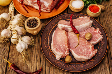 Assorted raw pork meat. Fresh loin, spices, fragrant vegetables and parsley