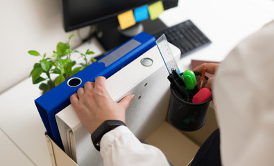 Businesswoman holding cardboard box with office stuff. Resignation concept.