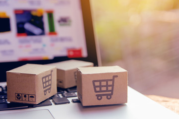 Online shopping - Paper cartons or parcel with a shopping cart logo on a laptop keyboard. Shopping service on The online web and offers home delivery..