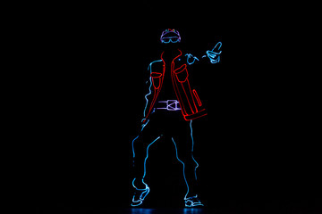 Dancer in suits with LED lamp. Silhouette of a man in a luminous suit on a black background. Neon costume. Entertainment.