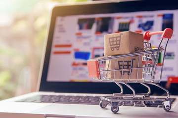 Shopping online. cardboard box with a shopping cart logo in a trolley on laptop keyboard. Shopping...