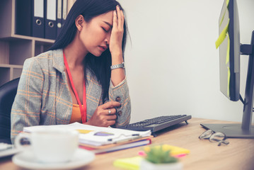 Stressed businesswoman,Frustrated and upset in business pressure and overworked at office. Adult Asian female working on laptop, feeling tire and headache. Stressed and Frustrated concept.