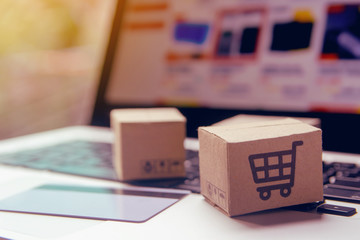 Online shopping - Paper cartons or parcel with a shopping cart logo and credit card on a laptop...