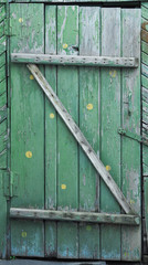 wooden door made of planks. painted with green paint with a yellow polka dot pattern. very old door, shabby, shabby and crooked. country style.