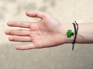 four leaf clover on the wrist of a young man. Shamballa bracelet with four leaf clover. copyspace.