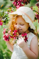 Fototapeta premium portrait of a little red-haired girl in Apple trees
