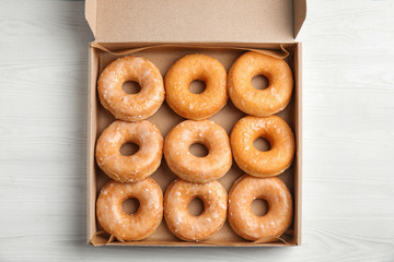 Delicious donuts on white wooden table, top view