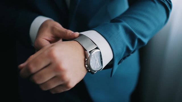 Close-up of a successful man is putting on a watch. Men's hand with a watch. Wedding day.